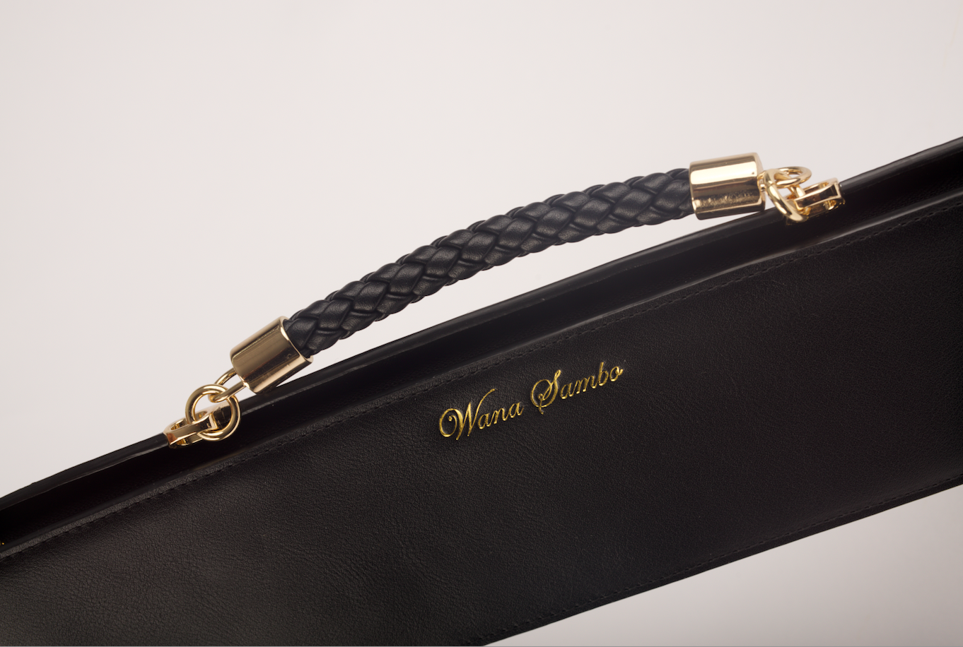Black leather strap with gold hardware on a product, featuring the brand 'Wana Sambo'.